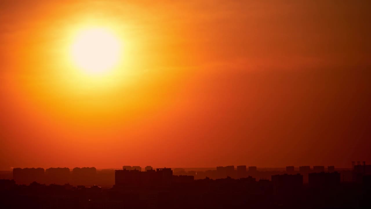 夕阳在红色的天空和黄昏的云在城市。夕阳西下，笼罩着城市的高楼大厦，时间流逝视频素材