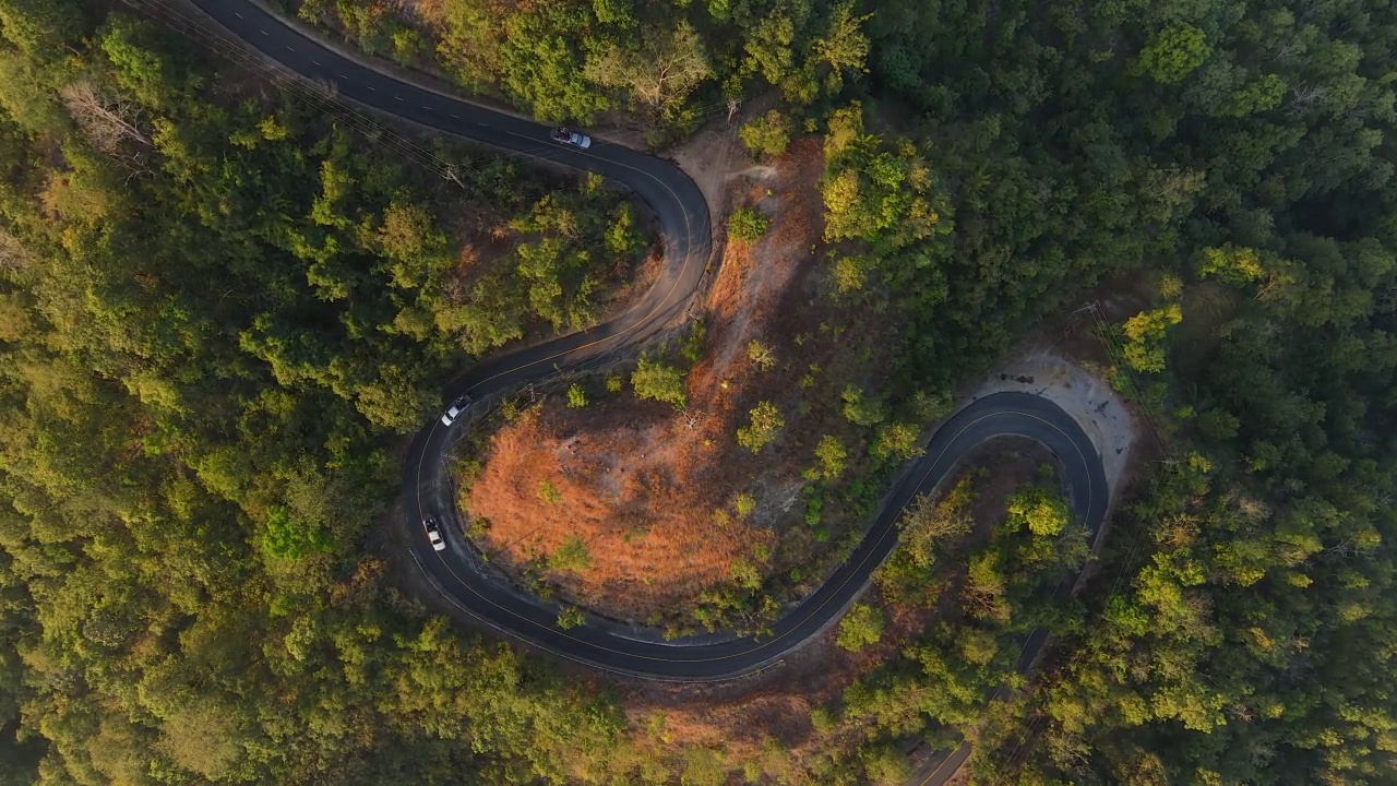 汽车行驶在道路上的鸟瞰图，蜿蜒穿过山上的绿色森林。视频素材