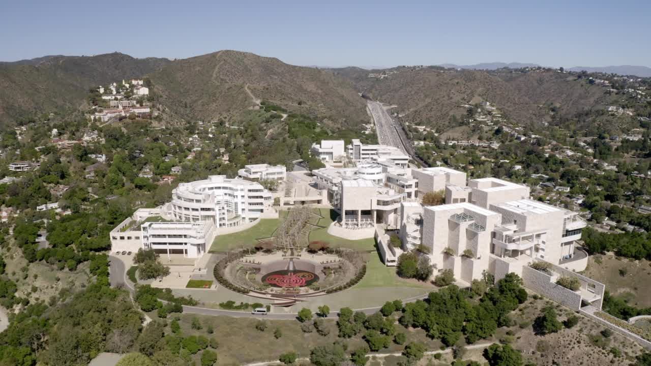 在阳光明媚的日子里，著名的盖蒂中心在城市道路上的山丘上的空中向前拍摄-洛杉矶，加利福尼亚视频素材