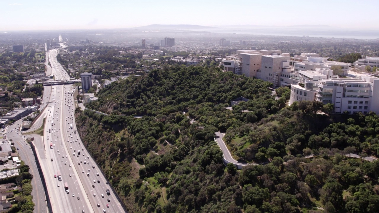 在自然山丘上的住宅建筑航拍，无人机在城市道路上向后飞行的汽车移动-比弗利山，加州视频素材