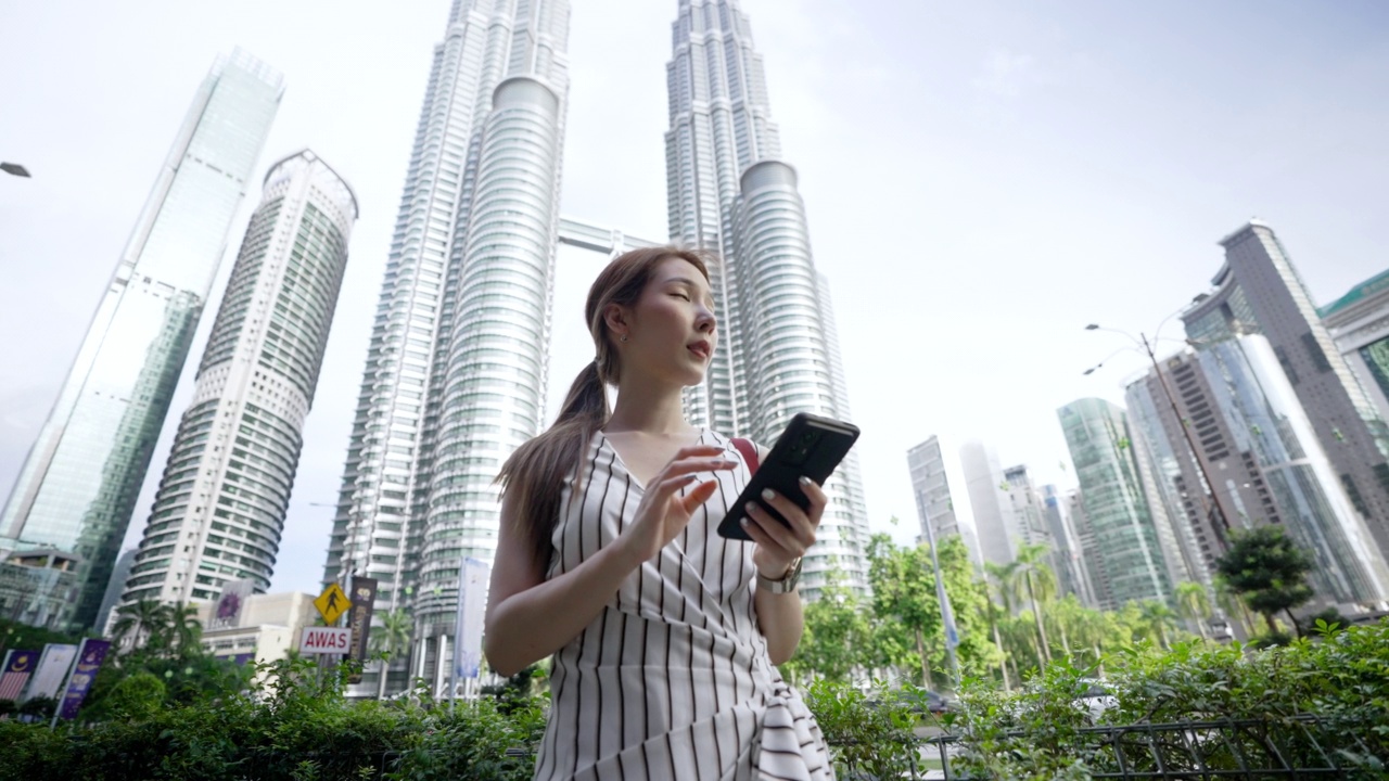 一名亚洲女性在吉隆坡市中心旅行时使用智能手机视频素材