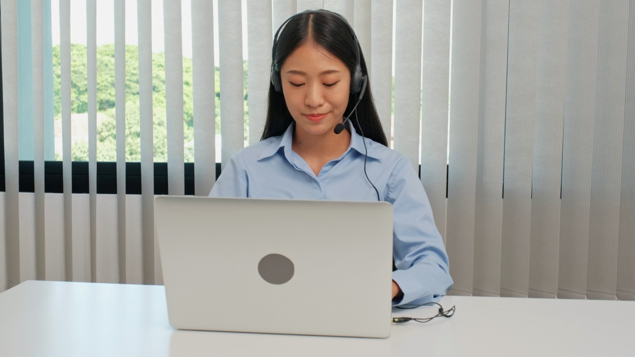 年轻的女商人在办公室的办公桌上戴着耳机讲电话视频素材