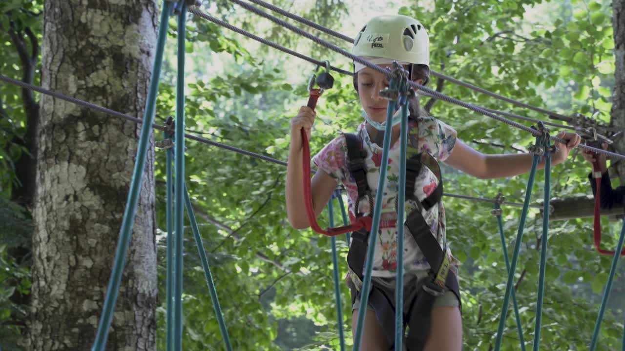 一个小女孩在冒险公园的索桥上走滑视频下载