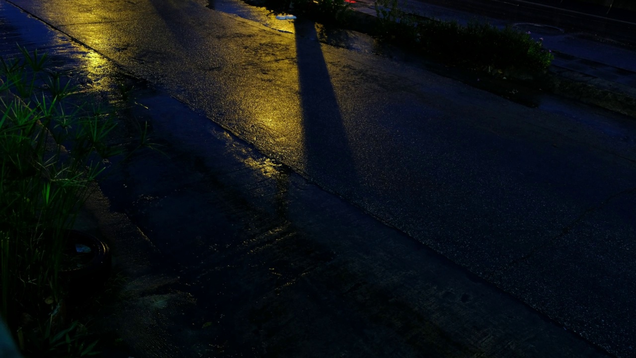 夏天的雨水滴成水坑在沥青上淹没街道，道路洪水由于晚上的雨水时间与路灯的反射。视频素材