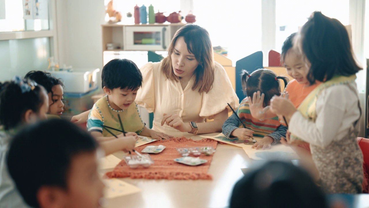 亚洲华人蒙台梭利幼儿园女教师在课堂上指导学生绘画视频素材画面1