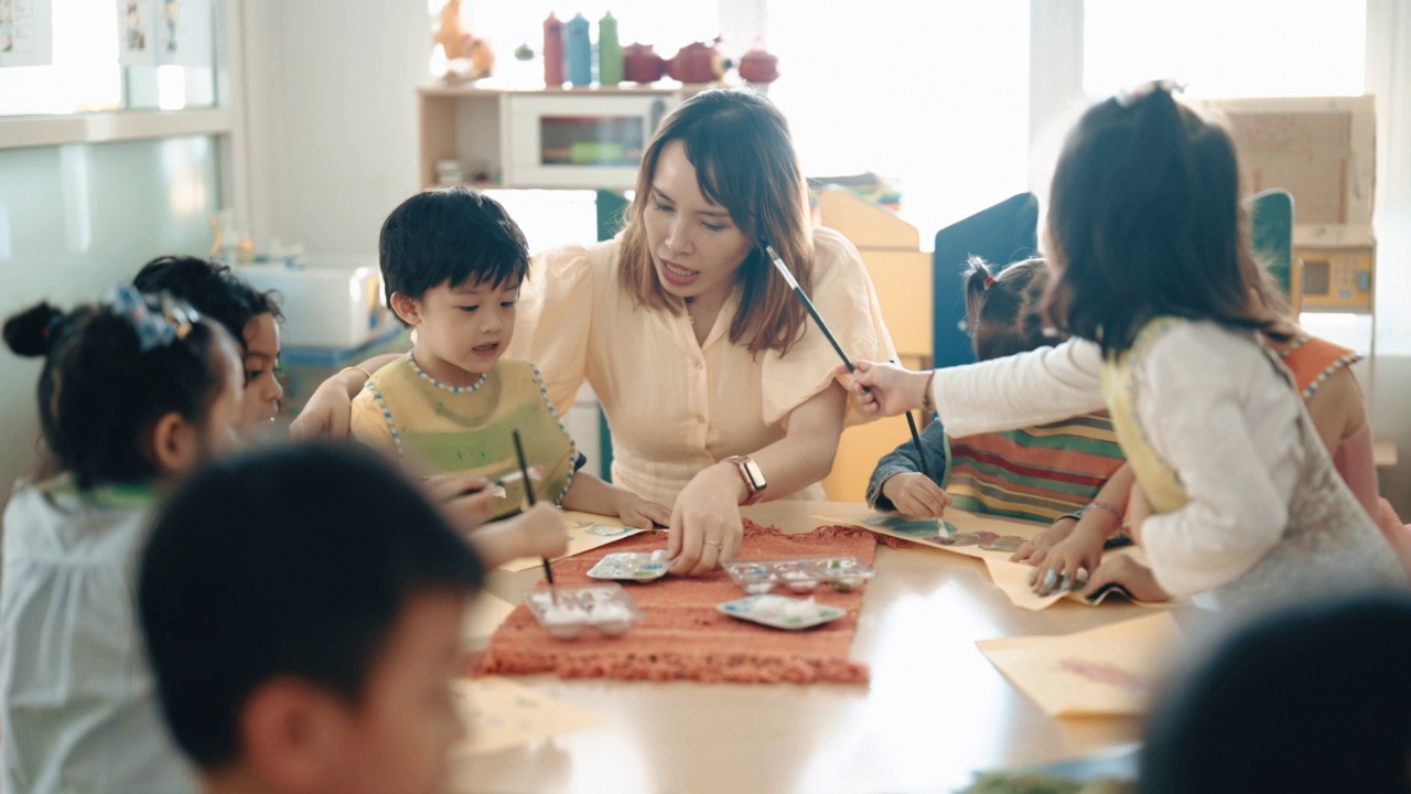 亚洲华人蒙台梭利幼儿园女教师在课堂上指导学生绘画视频素材画面2