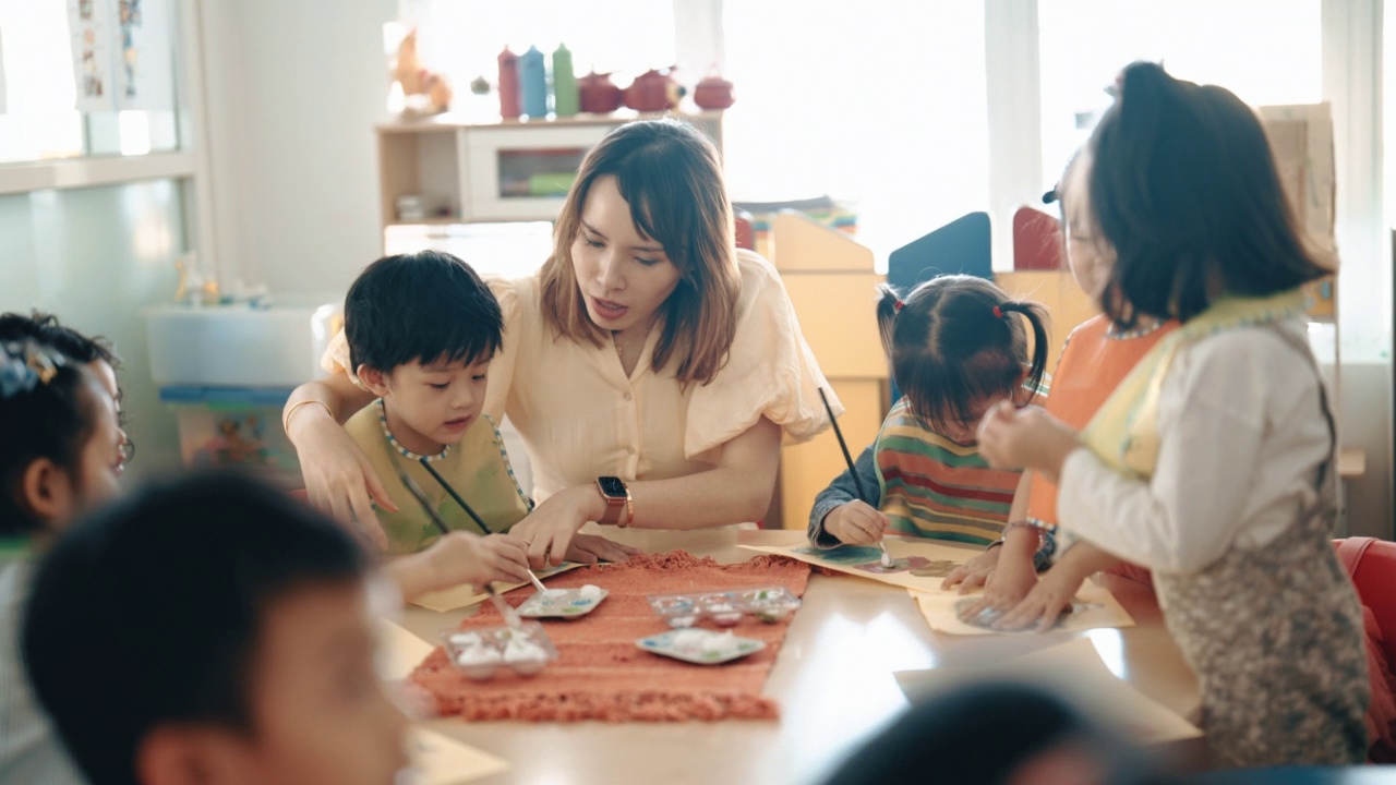 亚洲华人蒙台梭利幼儿园女教师在课堂上指导学生绘画视频素材画面3
