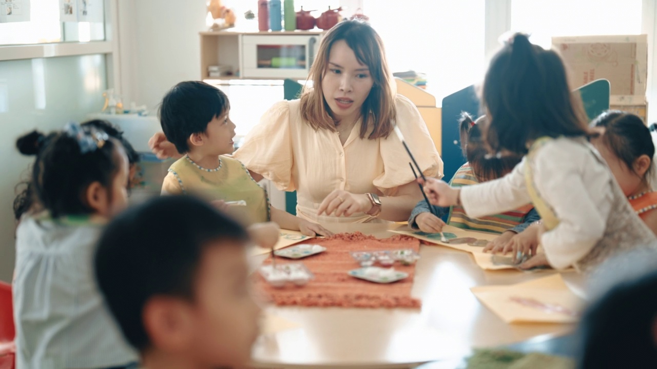 亚洲华人蒙台梭利幼儿园女教师在课堂上指导学生绘画视频素材画面4