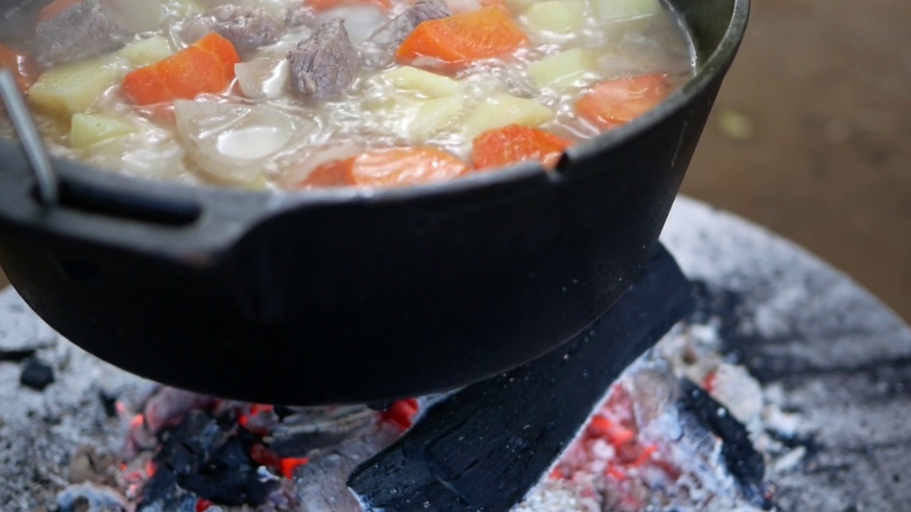 野外露营在营火上准备食物，野营旅行在营火上烹饪食物。营地厨房，在森林里生火做饭。煎锅着火了。露营生活的概念。视频素材