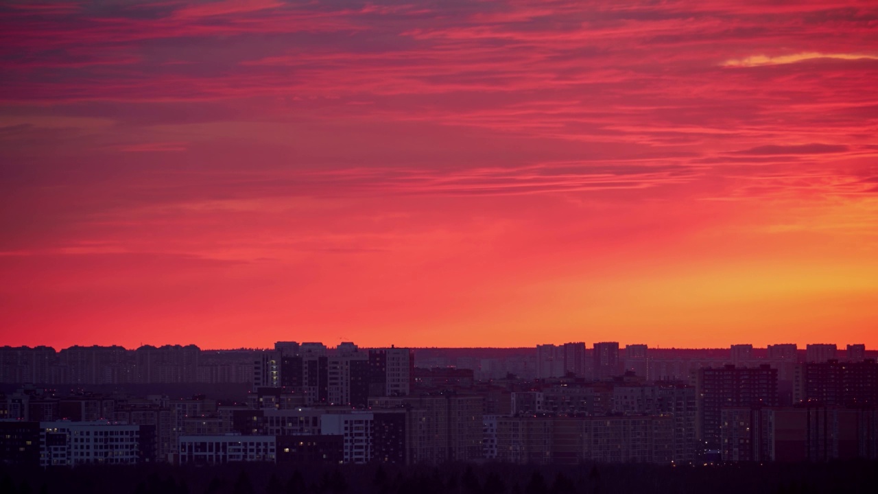 夕阳在红色的天空与晚霞在城市，时间流逝。夕阳西下，照耀着高楼林立的城市视频素材