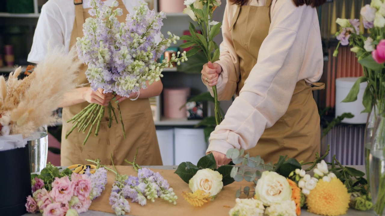 两名女花店工人在花店工作。漂亮的年轻女孩在工作场所制作玫瑰花和干花视频素材