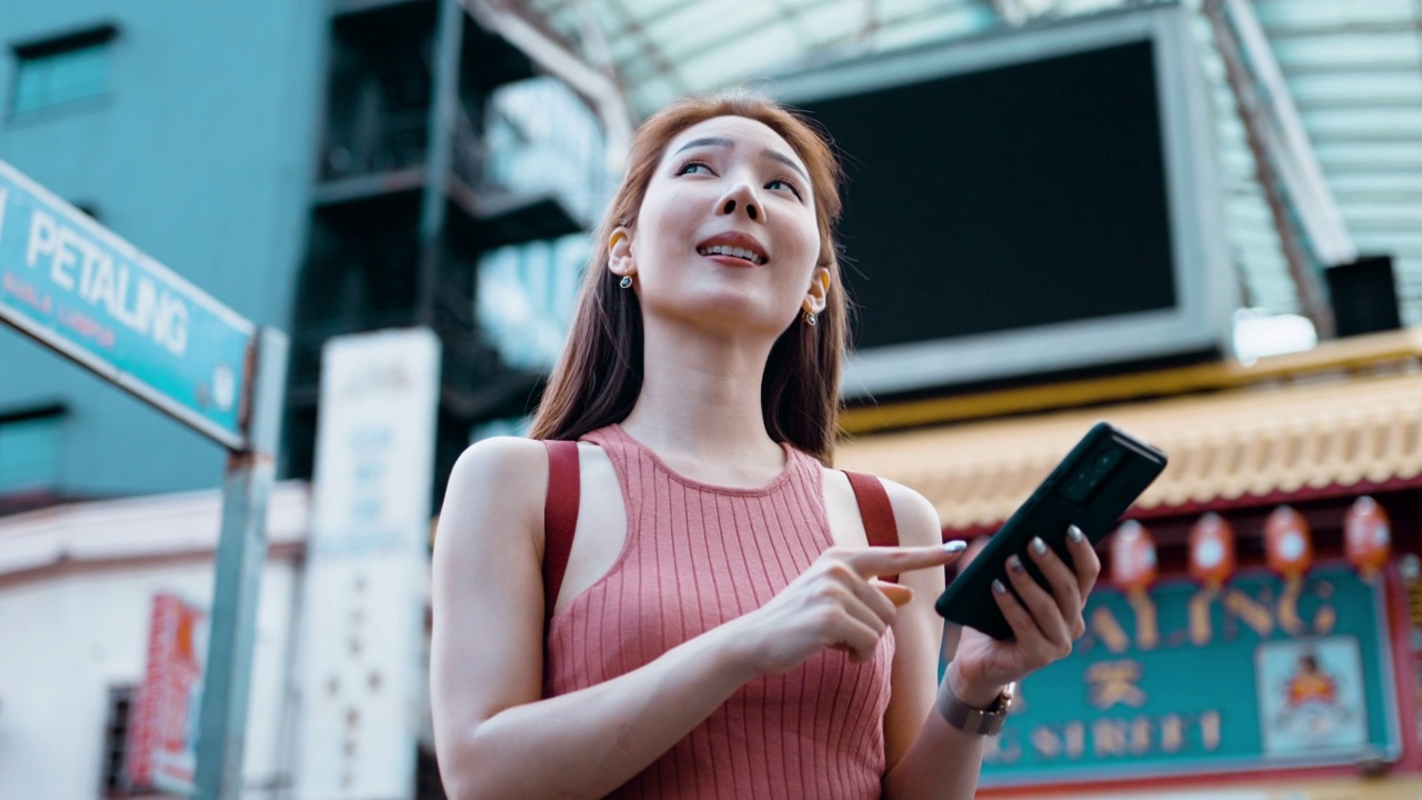 年轻的亚洲女性在八打岭街上旅行时使用智能手机视频素材