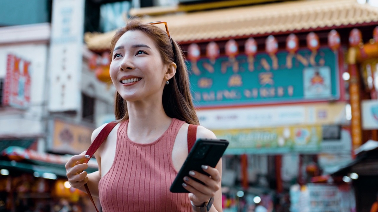 年轻的亚洲女性在八打岭街上旅行时使用智能手机视频素材