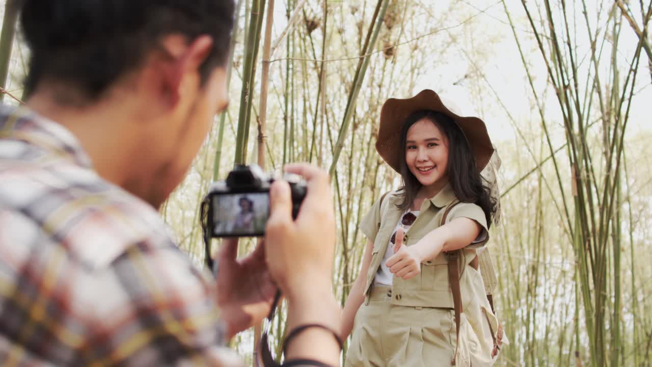 美丽的亚洲女性旅行者张贴行动拍照竹林，户外活动和自然的旅游理念视频下载