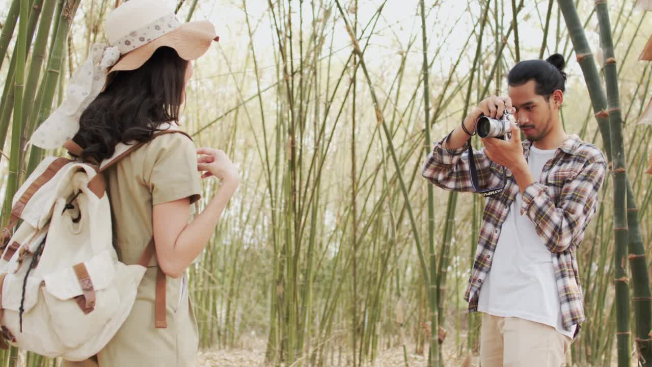 美丽的亚洲女性旅行者张贴行动拍照竹林，户外活动和自然的旅游理念视频下载