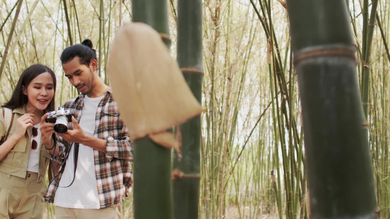 美丽的亚洲女性旅行者张贴行动拍照竹林，户外活动和自然的旅游理念视频下载