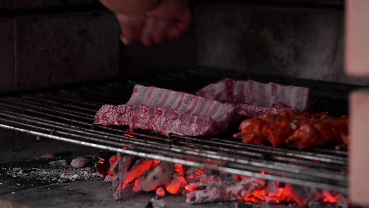 一名男子把腌好的猪排和鸡肉串放在烧烤架上，用木炭烤视频下载