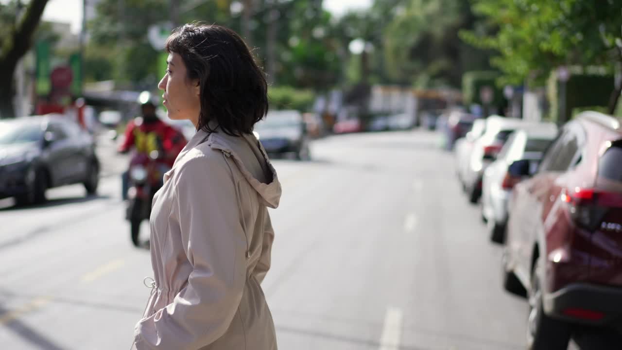 一位西班牙裔妇女穿过街道。城市中有人穿过人行横道视频素材