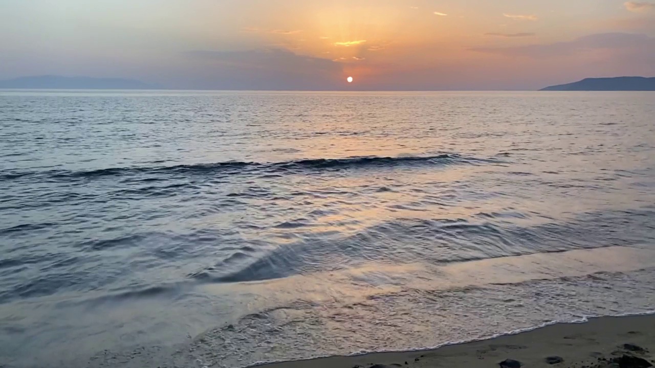 在美丽的夕阳下，海浪拍打着金色的沙滩。海浪拍打着海岸线。暑假与自然之美理念视频素材