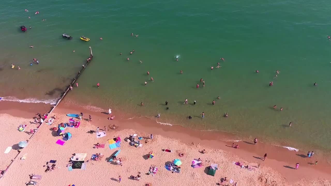 高角度海景海滩前与人在英国伯恩茅斯市，英国海洋的航拍镜头视频素材