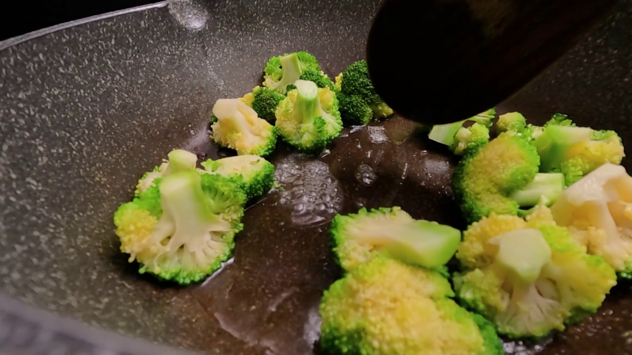 市场上新鲜的西兰花sautéed放在热煎锅里。视频素材画面2