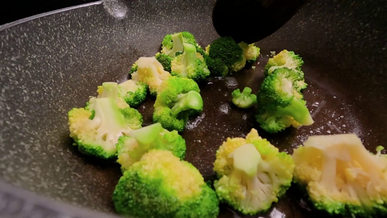 市场上新鲜的西兰花sautéed放在热煎锅里。视频素材画面3