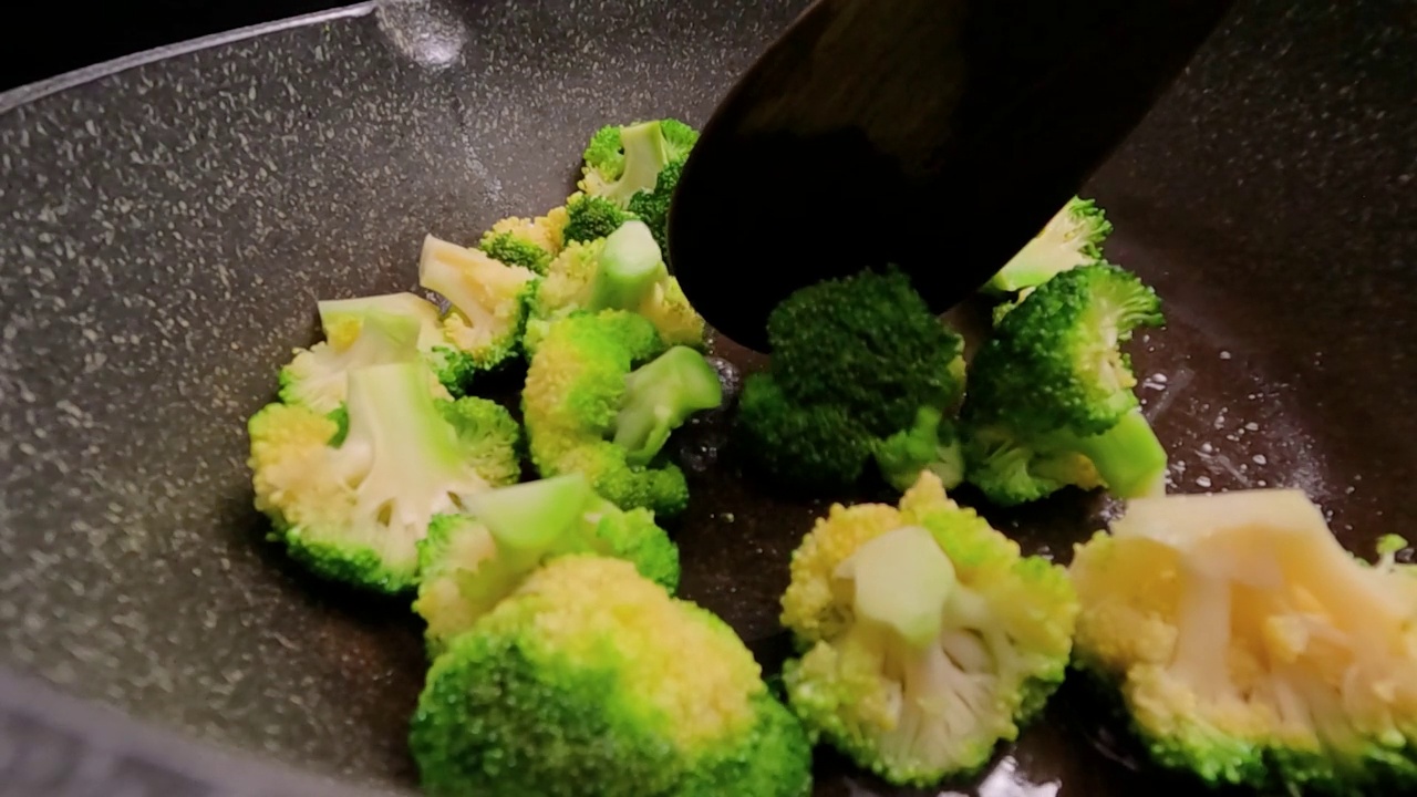市场上新鲜的西兰花sautéed放在热煎锅里。视频素材画面4