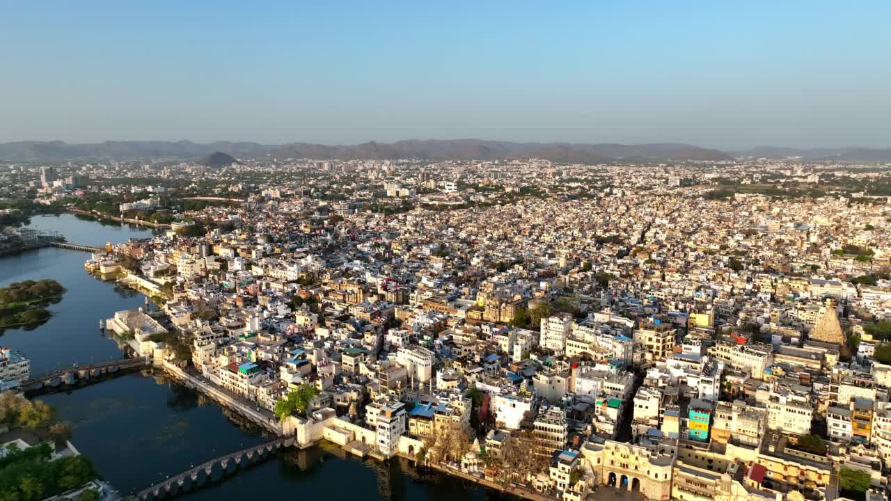 空中拍摄的城市景观上的住宅建筑，无人机在阳光明媚的日子在湖面上飞行-乌代普尔，印度视频素材