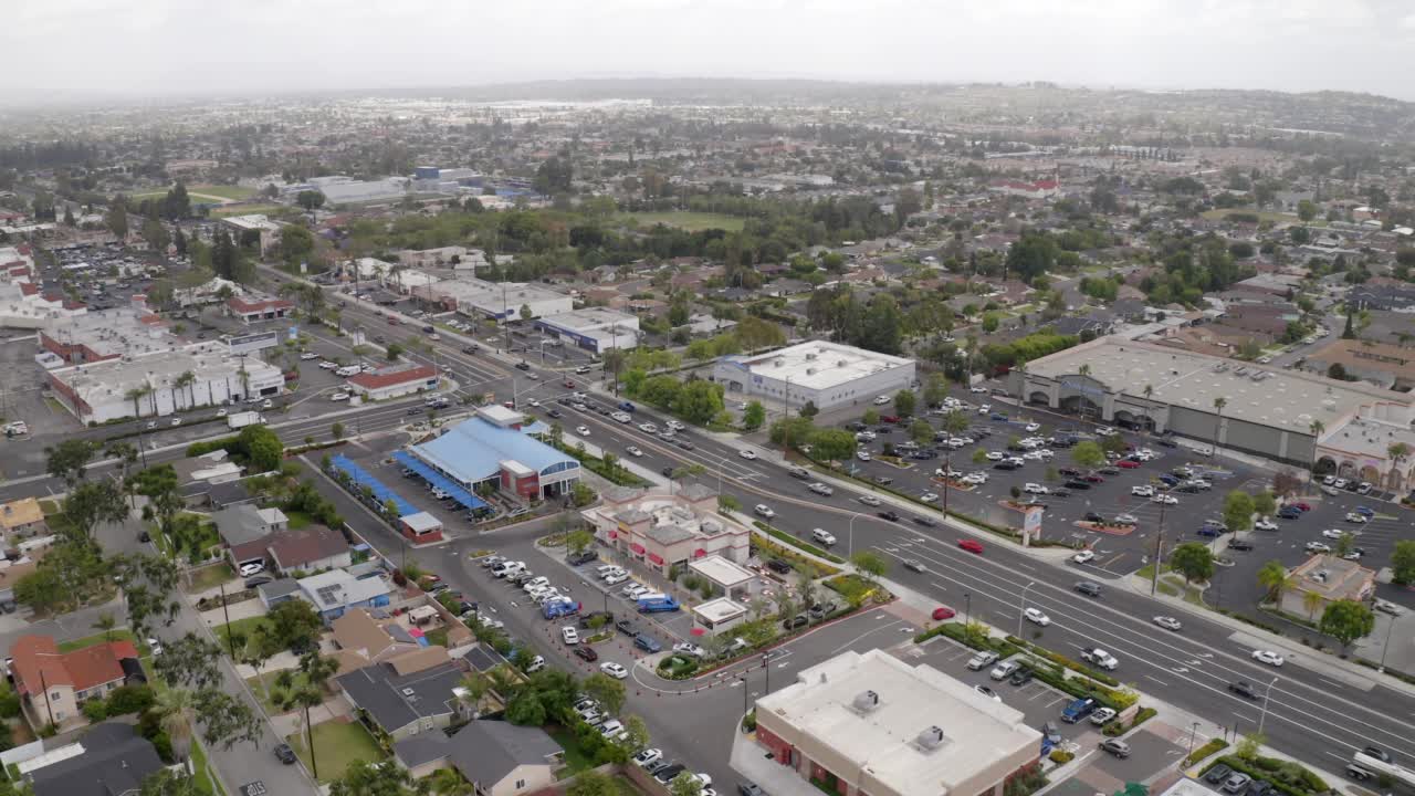 空中封锁拍摄的汽车移动在道路上的住宅城市对晴朗的天空-拉哈布拉，加州视频素材