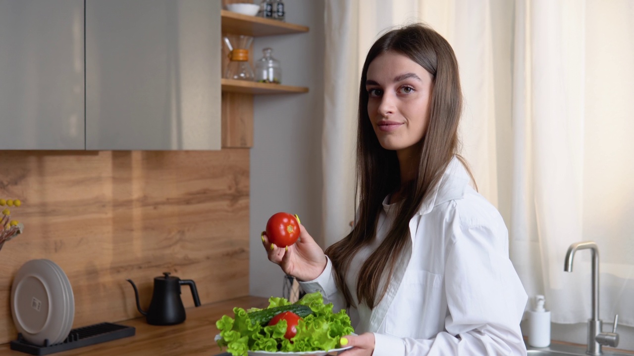 健康食品。素食沙拉。饮食。美丽的年轻女子正在厨房里准备蔬菜沙拉。节食的概念。健康的生活方式。在家做饭视频素材