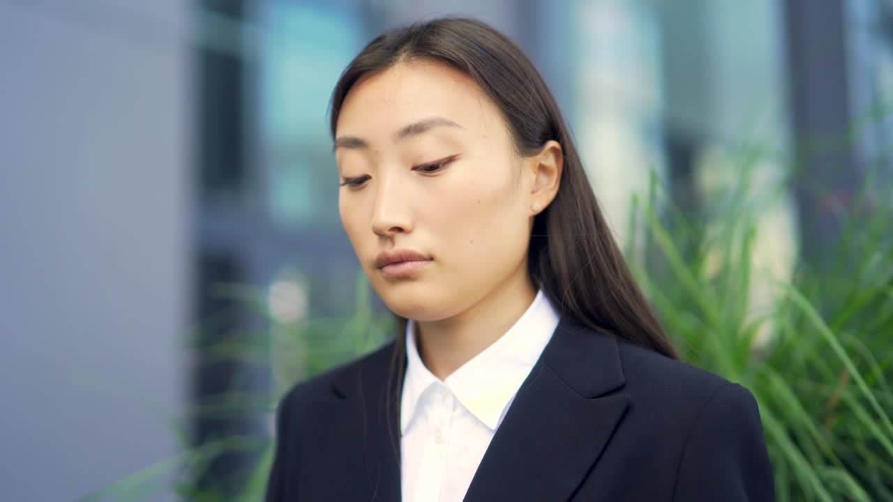 亚洲女性办公室职员放松，冥想户外坐在城市背景的长椅上，城市公园休息休息商务女性员工在正式的西装，闭上眼睛视频素材