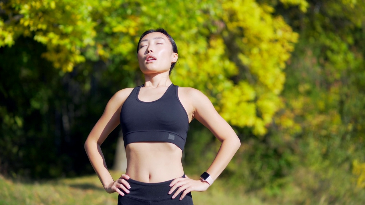 特写肖像年轻快乐fit亚洲妇女站在森林树木之间的自然放松，呼吸新鲜空气闭上眼睛。女性享受平静平静的生活视频素材