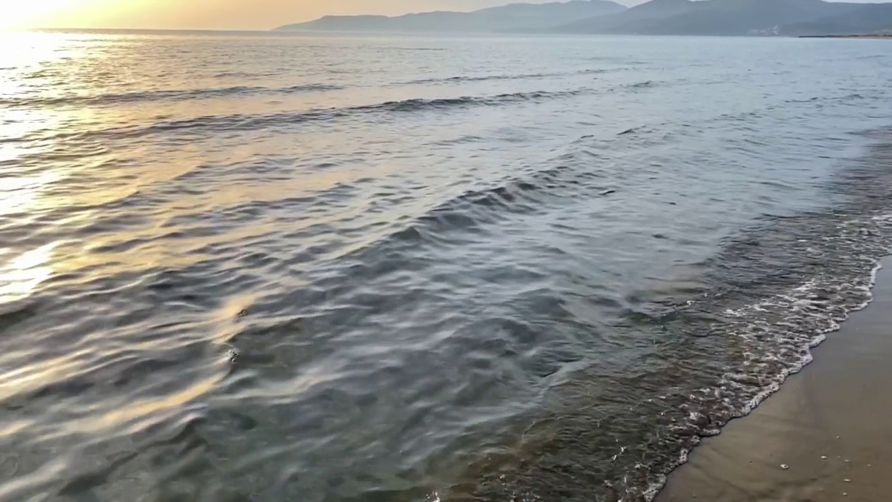 日落时海浪拍打金色沙滩的慢动作。海浪拍打着海岸线。暑假与自然之美理念视频素材