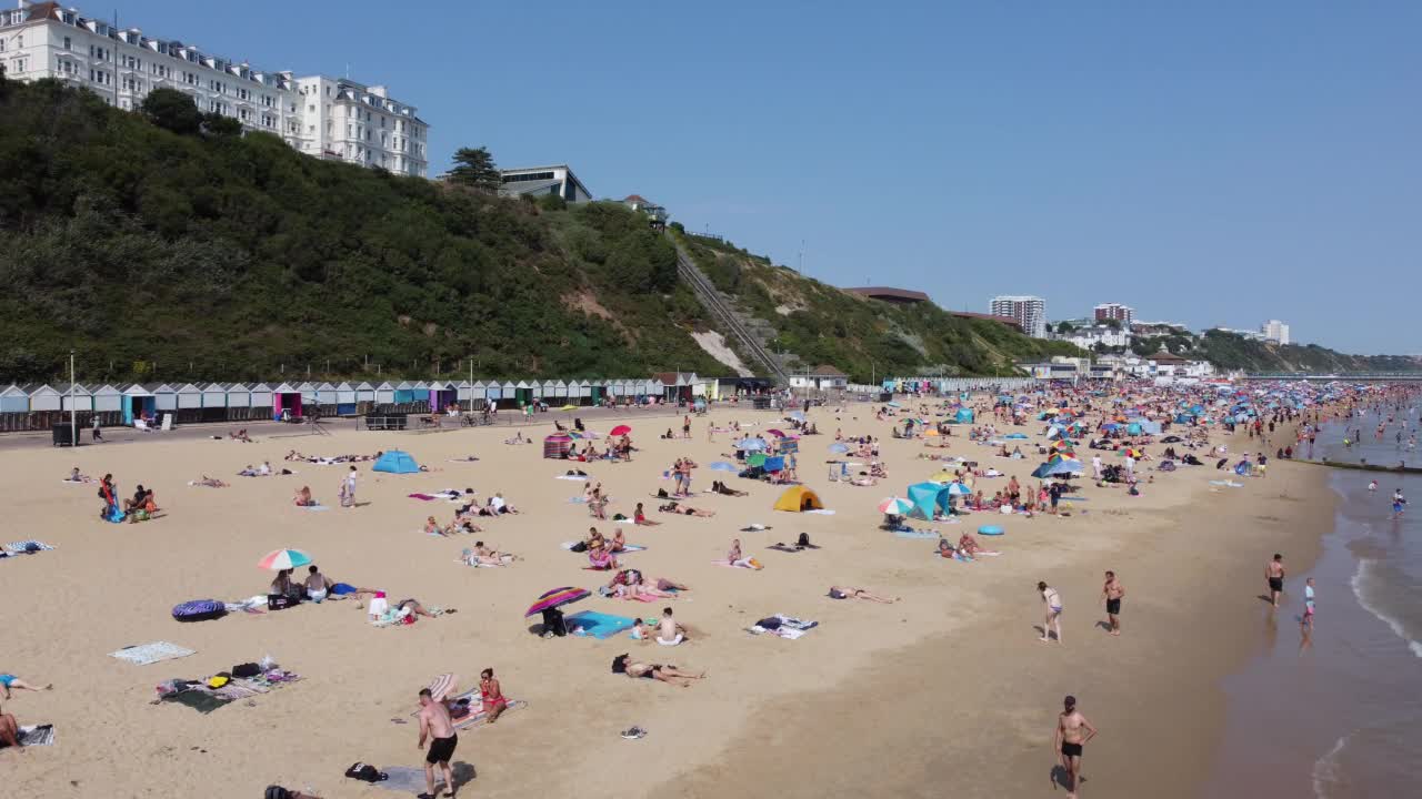 高角度海景海滩前与人在英国伯恩茅斯市，英国海洋的航拍镜头视频素材