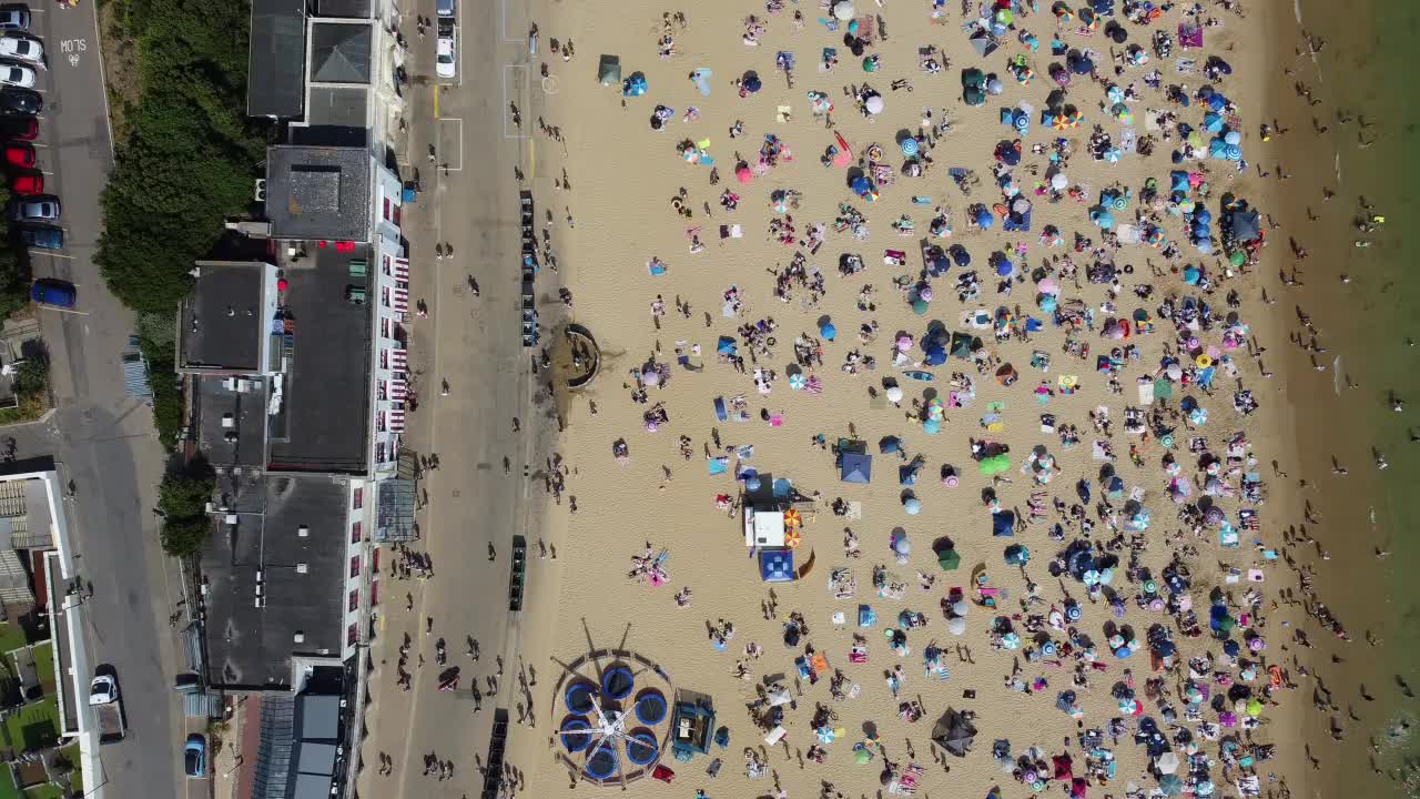 高角度海景海滩前与人在英国伯恩茅斯市，英国海洋的航拍镜头视频素材