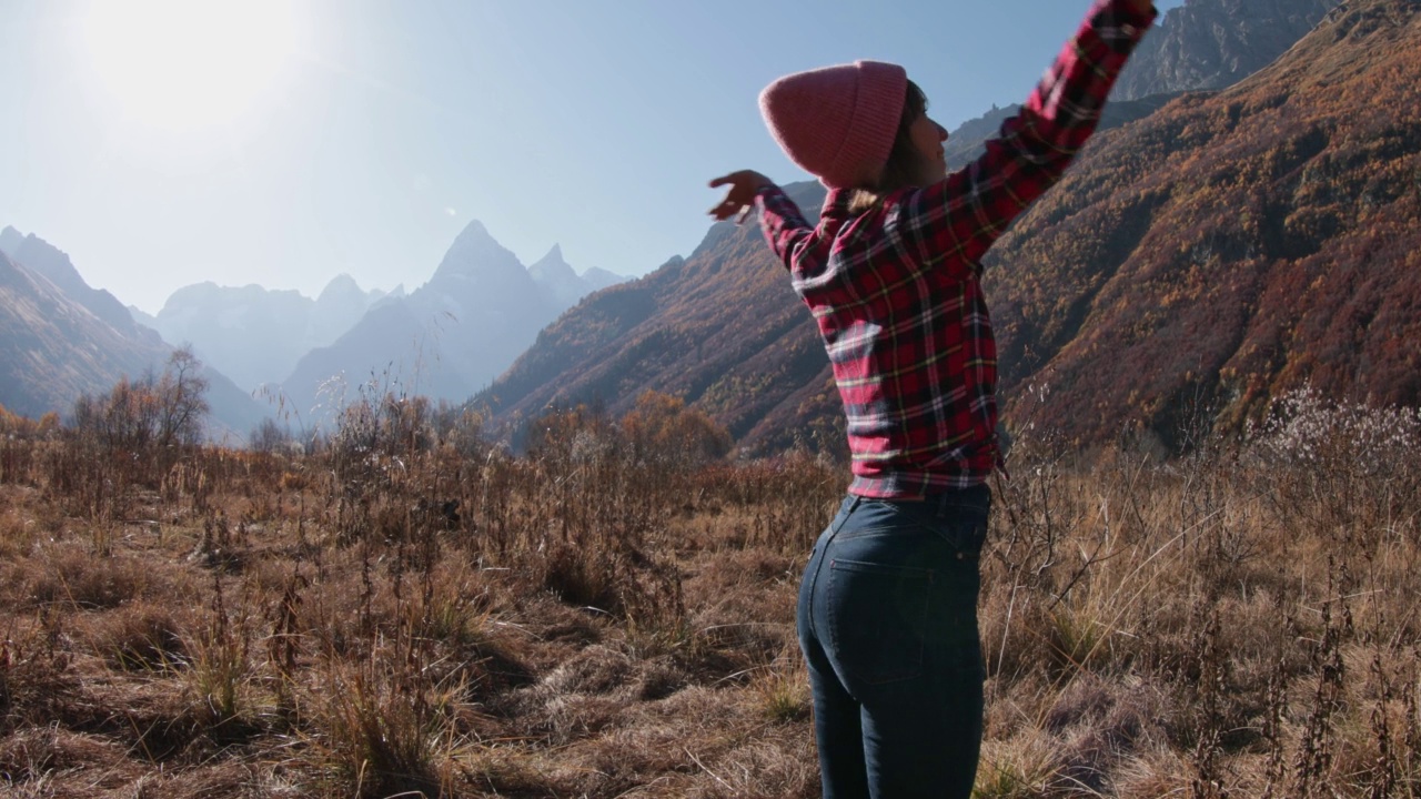 年轻女子在秋日的山间徜徉。登山和快乐的徒步旅行者视频素材