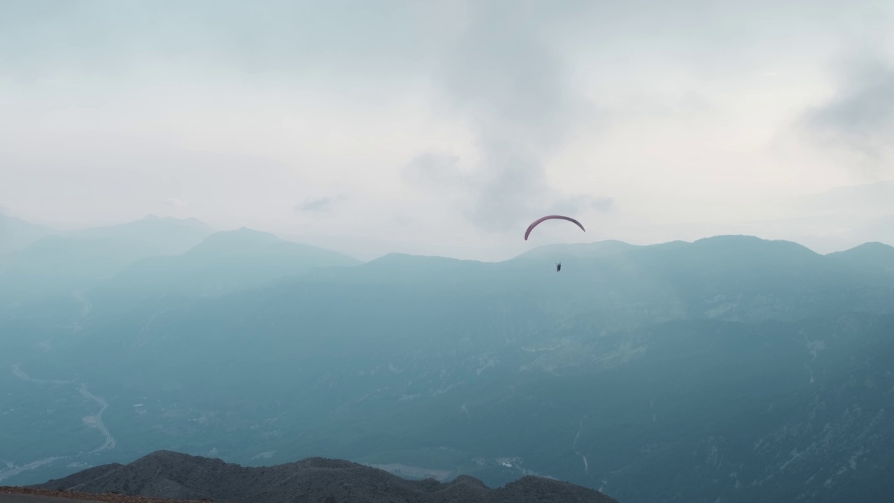 人们驾驶滑翔伞飞越高山。视频下载