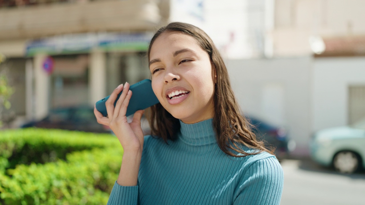 年轻的非洲裔美国女性微笑着自信地在街上用智能手机听语音信息视频素材