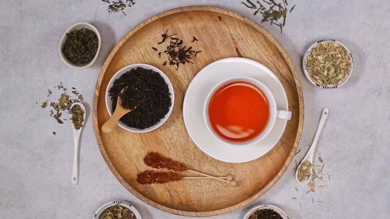 白杯红茶，干红茶加糖。在陶瓷勺上晾晒各种茶叶。视频下载