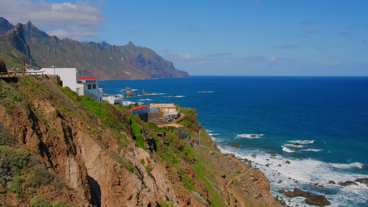 在加那利群岛特内里费岛的贝尼霍海滩，海浪撞击岩石，浪花飞溅。木楼梯通向大海。前景是小村庄，建筑物。视频素材