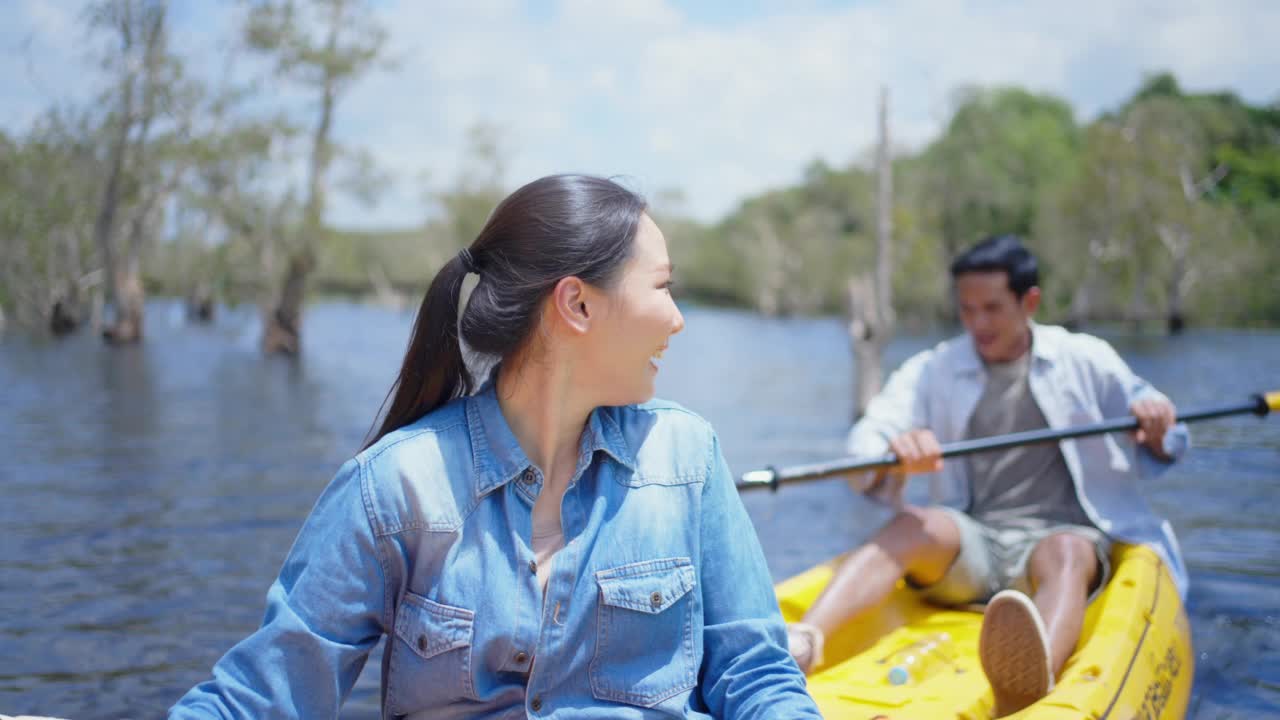 年轻的亚洲夫妇在夏季旅游假期的红树林划皮艇。视频素材