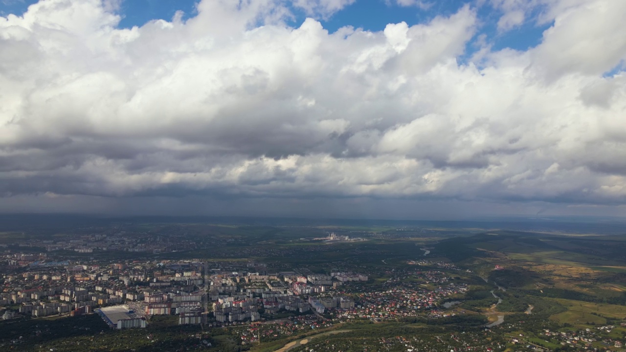 高空鸟瞰图，远处的城市被暴雨前形成的蓬松积云所覆盖视频素材