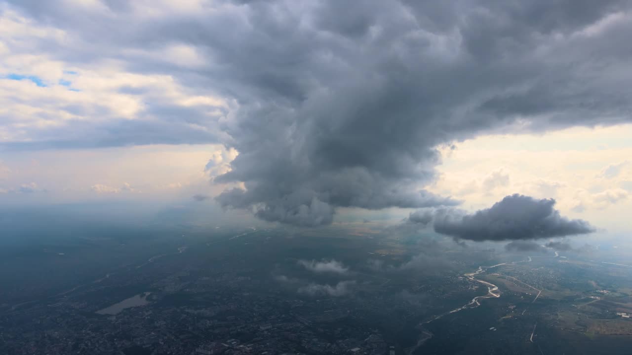 在暴风雨来临前，远处的城市在高空被膨胀的积云覆盖的飞机窗口鸟瞰图视频素材