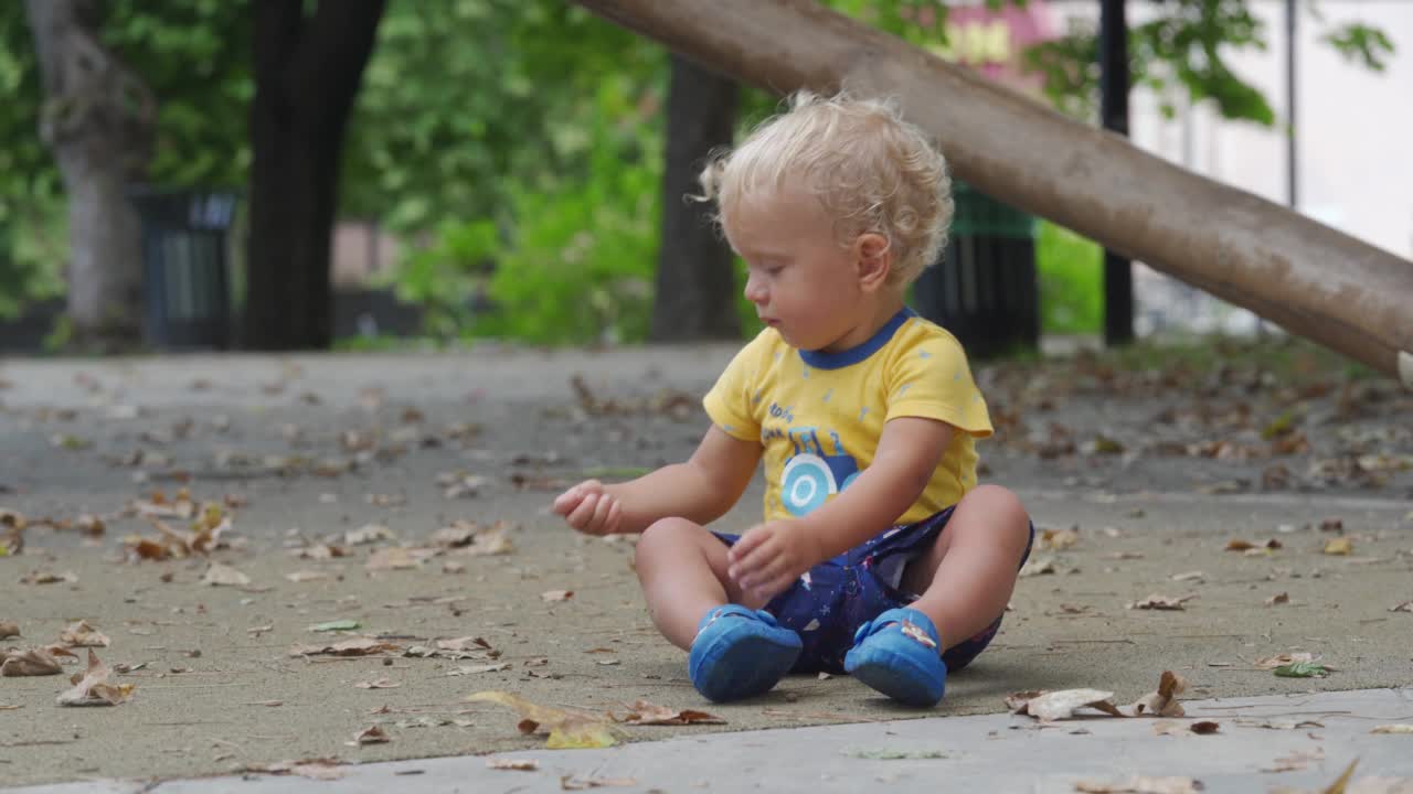 孩子在雨后潮湿的操场上玩耍，快乐的1.5岁幼童在一个雨天的夏天在公园里。儿童户外活动。视频素材