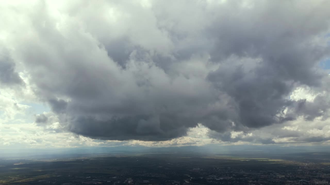 高空鸟瞰图，远处的城市被暴雨前形成的蓬松积云所覆盖视频素材