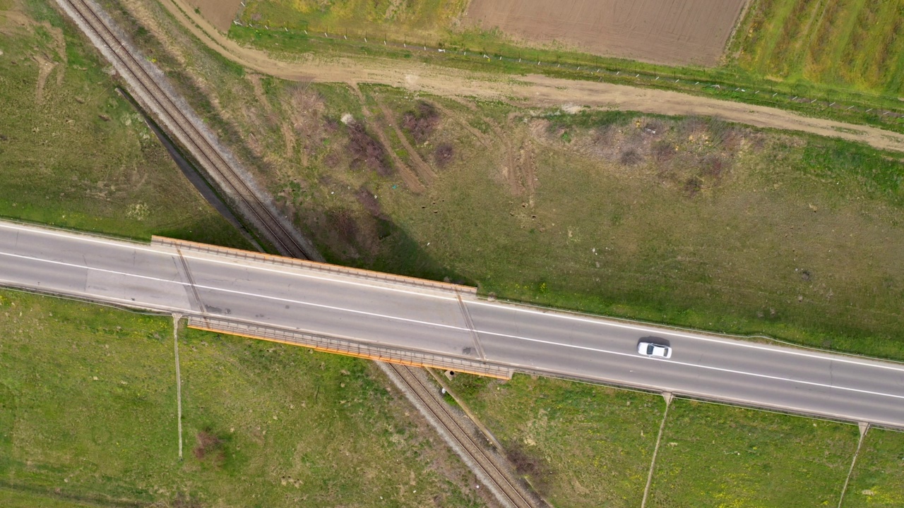 在高速公路上穿越铁路立交桥的汽车，从无人机视角俯视视频素材