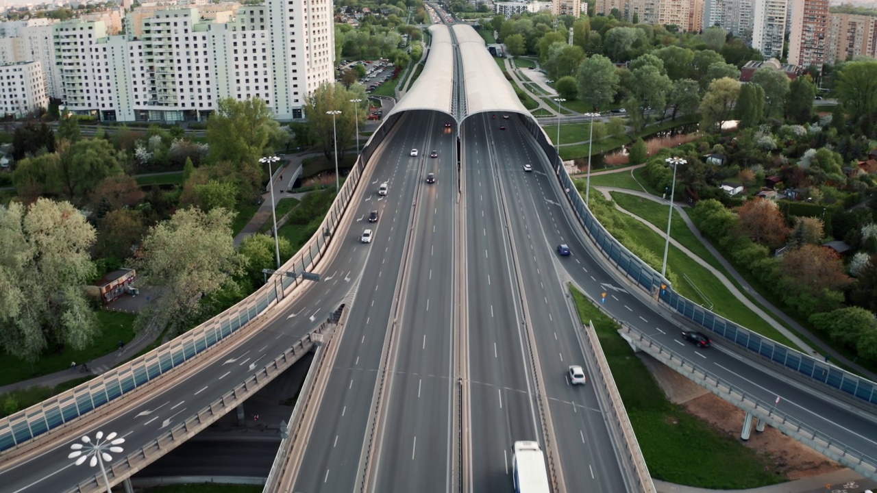 航拍高架多路交汇处。无人机拍到阳光明媚的傍晚城市高速公路路口。十字路口高速公路立交桥。夏日，绿树绿草视频素材