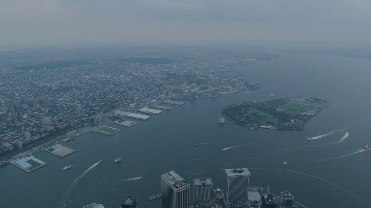 空中平移从曼哈顿的顶端向右面对南部的总督岛，纽约港，埃利斯岛，和自由女神像。在港口可以看到船只、游艇和渡轮。炮台公园部分可见视频素材