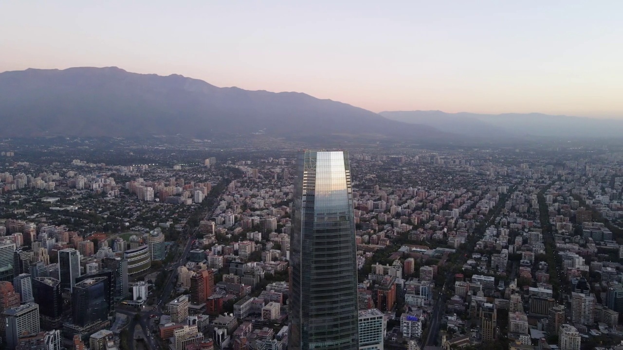 科斯坦纳拉中心摩天大楼和马波乔河的空中视差，背景是拉蒙山，在圣哈坦地区在蓝色时间，智利首都圣地亚哥视频素材