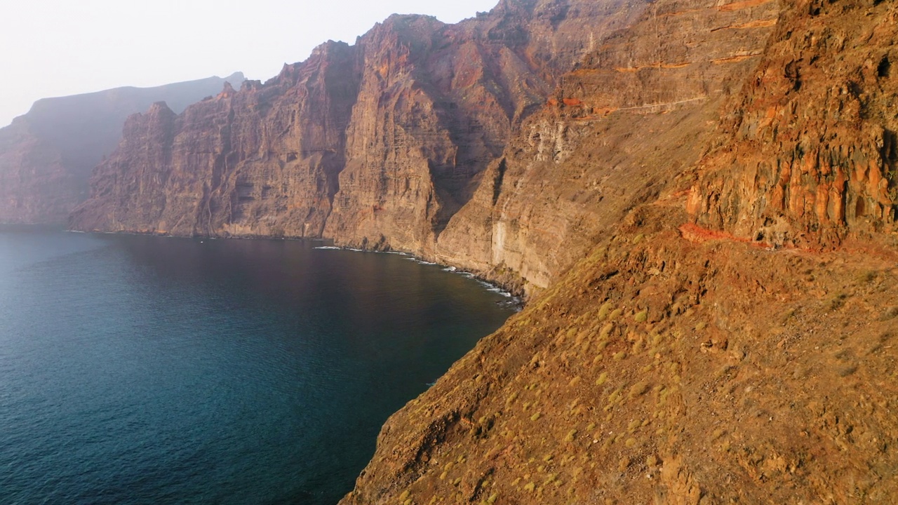 海洋的日落。阳光反射在陡峭的岩石上，电影般的自然景观。危险的洛斯巨人悬崖。寒冷晴朗的冬日早晨。阳光照亮了沙漠山脉的纹理。特内里费岛视频素材